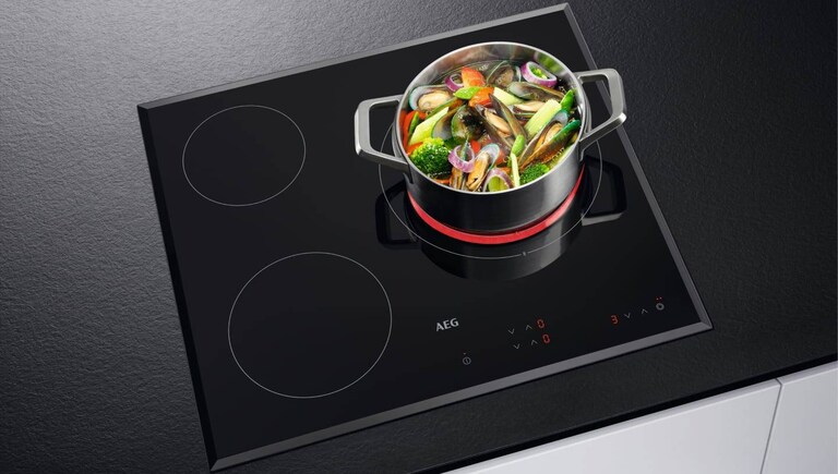 Comida a cozinhar numa panela colocada numa placa de indução AEG.